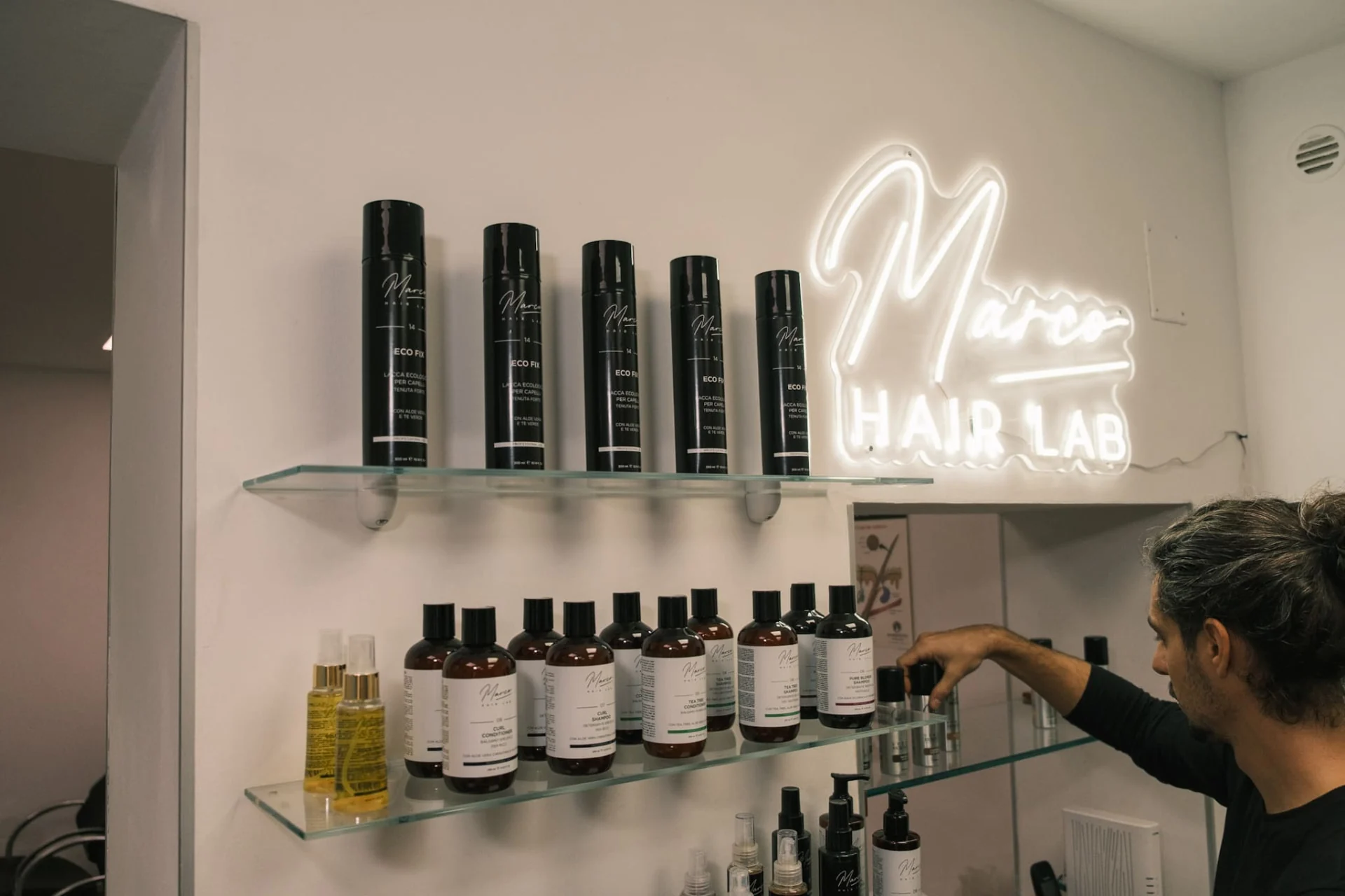 Marco seleziona i prodotti per capelli sugli scaffali del suo Hair Lab
